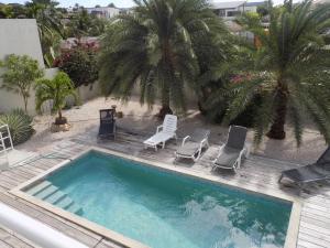 a pool with chairs and palm trees on a balcony at Favvidea in Jan Thiel