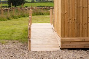 a wooden walkway leading to a wooden fence at Eden Valley by Wigwam Holidays in Cumwhinton +7 photos