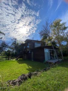 a house on a grassy field with a cloudy sky at Pousada Vale de Luz FW in Frederico Westphalen