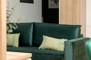 a green leather couch with two pillows on it at Cozy Studio with Parking in Poznań by Noclegi Renters in Poznań