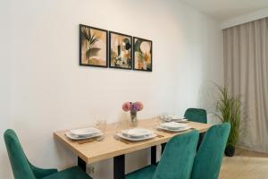 a dining room with a wooden table and green chairs at Cozy Studio with Parking in Poznań by Noclegi Renters in Poznań