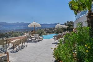 a patio with chairs and umbrellas and a swimming pool at Alexandras's Mansion in Ayiá