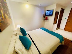 1 dormitorio con 1 cama con almohadas azules y TV en Hotel Santa Cruz Bogotá, en Bogotá