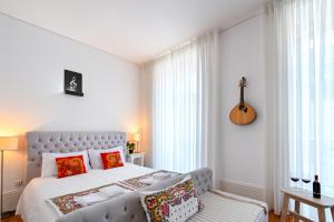 ein Schlafzimmer mit einem Bett und einer Gitarre an der Wand in der Unterkunft Almada e Fado in Porto