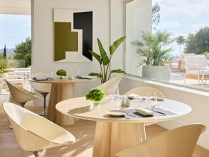 a restaurant with tables and chairs with a view of a patio at The Roc Club, A Grecotel Hotel to Live in Athens