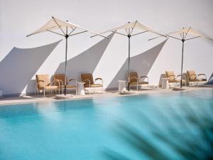 a group of chairs and umbrellas next to a swimming pool at The Roc Club, A Grecotel Hotel to Live in Athens