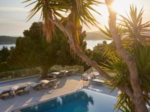 a swimming pool with lounge chairs and palm trees at The Roc Club, A Grecotel Hotel to Live in Athens