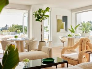 a living room with tables and chairs and plants at The Roc Club, A Grecotel Hotel to Live in Athens