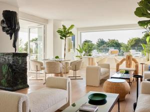 a living room with chairs and tables and a large window at The Roc Club, A Grecotel Hotel to Live in Athens