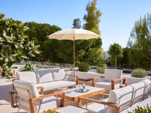 a patio with chairs and a table with an umbrella at The Roc Club, A Grecotel Hotel to Live in Athens