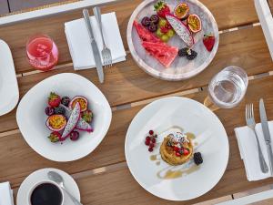 a wooden table with plates of food on it at The Roc Club, A Grecotel Hotel to Live in Athens