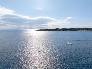three white sails in the water with an island at The Roc Club, A Grecotel Hotel to Live in Athens