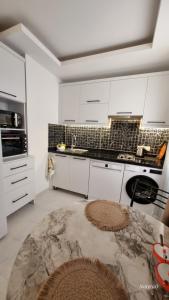 a white kitchen with white cabinets and a table at Aygun Apart 4 in Mahmutlar
