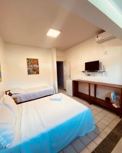 a hotel room with two beds and a flat screen tv at Suites Enseada Beira Mar in Coruripe
