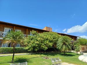 a house with two chairs and palm trees in the yard at Akirá Pousada in Aquiraz