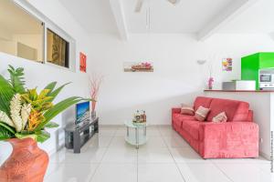 a living room with a red couch and a tv at Basilic au Refuge de Madiana à Schoelcher in Schœlcher