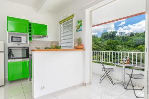 a kitchen with green cabinets and a balcony at Basilic au Refuge de Madiana à Schoelcher in Schœlcher