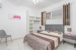 a bedroom with a large bed and a chair at Basilic au Refuge de Madiana à Schoelcher in Schœlcher