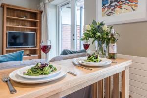 a table with two plates of food and wine glasses at Captain's Quarters, a ground floor apartment in Aldeburgh in Aldeburgh