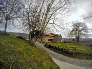 a house on the side of a field with a dirt road at Casa Quintas dos Mouros in Montederramo