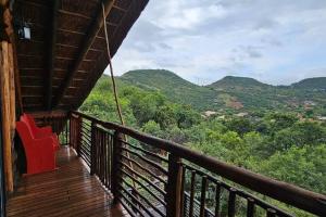 Una habitación con un balcón con una silla roja encima. en Breakaway Bushveld Mansion at Olifantsrivier ,Presidentsrus, en Botshabelo