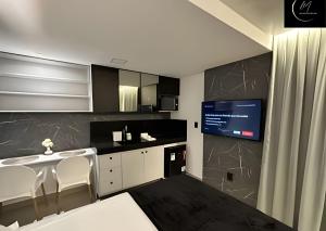 eine Küche mit weißen Stühlen und ein TV an der Wand in der Unterkunft LM Get One in João Pessoa
