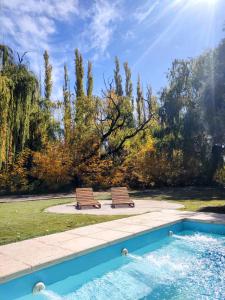 two benches sitting next to a swimming pool at Hostel Barreal in Barreal