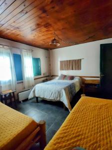 a bedroom with two beds and a wooden ceiling at Hostel Barreal in Barreal