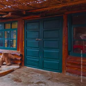 a green garage door in a house with windows at La cabaña estancia Los Tilos in Hacienda Santo Domingo