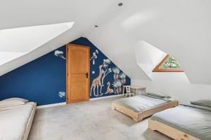 a attic room with two beds and a blue wall at Magnifique Villa, 1H de Paris, Piscine chauffée ! in Labosse +43 photos