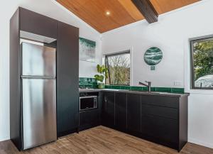 a kitchen with black cabinets and a stainless steel refrigerator at Black Label Retreats in Gisborne +11 photos