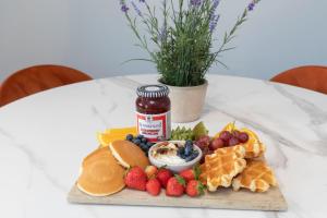 ein Teller mit Essen mit Marmelade und Obst auf einem Tisch in der Unterkunft Elliot Oliver - Cosy 2 Bedroom Town Centre Apartment in Cheltenham + 12 Fotos