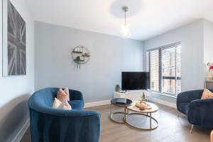 ein Wohnzimmer mit 2 blauen Stühlen und einem TV in der Unterkunft Elliot Oliver - Cosy 2 Bedroom Town Centre Apartment in Cheltenham