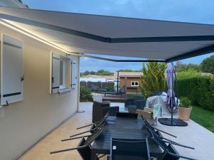 a patio with chairs and a white patio umbrella at CHAMBRE D HÔTE CHEZ Nath in Sadirac