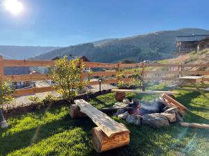 a fire pit in the grass next to a wooden fence at Sonnberg Chalet - Entspannung pur im Luxus Chalet mit Whirlpool-Sauna in Lachtal +63 photos