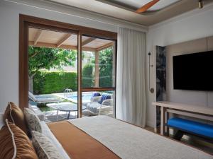 コリンビアにあるAtlantica Holiday Village Rhodesのベッドルーム(ベッド1台、テレビ、パティオ付)