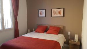 una camera da letto con un letto con cuscini rossi e una finestra di Coquette maison canetoise a Canet-en-Roussillon