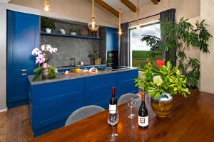 a kitchen with blue cabinets and two bottles of wine on a table at Villa Una Sofia in Pazin