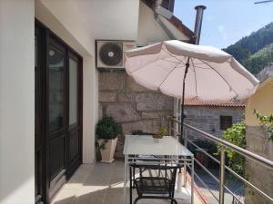a pink umbrella and a table and chairs on a balcony at Alojamento Casa da Eira in Geres