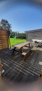 a picnic table on a deck with a playground at Gite châlet nature haute vosges in Anould
