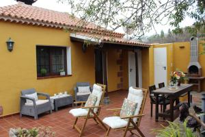 un patio con sillas y una mesa frente a una casa amarilla en La Casita de Ana, en Puntagorda