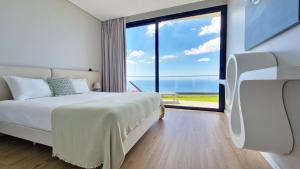 ein Schlafzimmer mit einem Bett und einem großen Fenster in der Unterkunft Villa Estrelícia by LovelyStay in Ribeira Brava + 49 Fotos