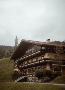 a large building on a hill next to a field at Pension Mühlbacherhof in Mühlbach am Hochkönig