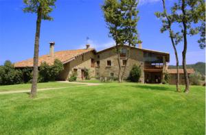 una gran casa de piedra con un patio verde en Mas la Serra, en Rupit