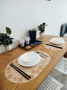 a wooden table with plates and chopsticks on it at Cozy Haven Superior Studio Free Private Parking Netflix in Petaling Jaya