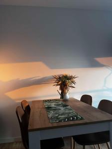 une table à manger avec des chaises et un vase avec une plante dans l'établissement Leaf Apartament Łódź prywatne miejsce parkingowe, à Łódź