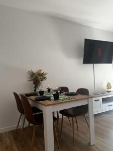 une table à manger avec des chaises et une télévision dans l'établissement Leaf Apartament Łódź prywatne miejsce parkingowe, à Łódź
