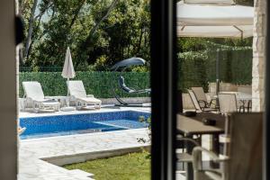 a view of a pool with chairs and an umbrella at Villa Goranovic in Herceg-Novi