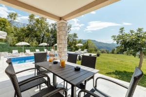 a patio with a table and chairs and a pool at Villa Goranovic in Herceg-Novi