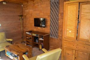 a living room with a table and a tv and a wooden wall at Viehaus in Villa La Angostura